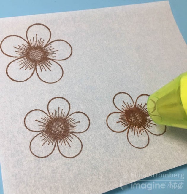 I started with stamping and heat embossing simple flower images on a piece of vellum.